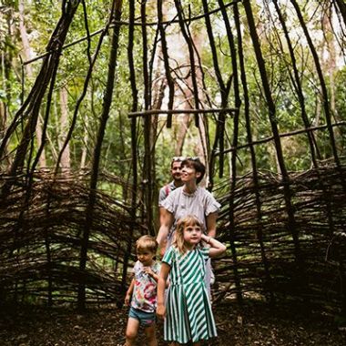 Een gezin met twee jonge kinderen gaat een wilgenhut in het Trollenbos van De Schorre in Boom binnen. Het wilgenriet is niet aansluitend, waardoor er licht binnenkomt, voornamelijk langs de bovenkant. De vrouw kijkt naar de dakconstructie boven haar dat licht doorlaat. Ze moedigt de kinderen met een klein duwtje in de rug aan om verder te wandelen, terwijl haar man achter haar volgt. De kinderen kijken vol bewondering rondom zich.