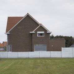 Een huis, grasveld en bedrijfsgebouw tonen de overgang van landelijkheid naar stedelijkheid