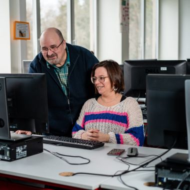 Een leerkracht geeft uitleg aan een cursist aan de computer