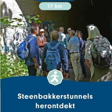 De cover van de brochure 'Steenbakkerstunnels herontdekt' (2023) toont een groep wandelaars bij een ingang van een steenbakkerstunnel. Een gids geeft hen uitleg.