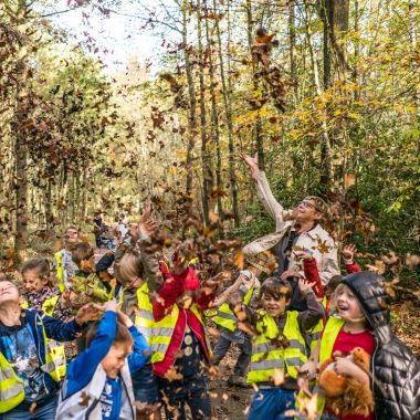 Kinderen gooien bladeren op in de herfst