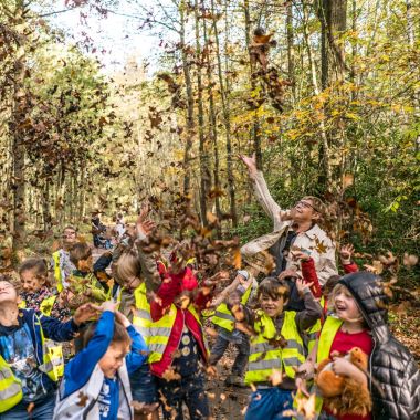 Kinderen gooien bladeren op in de herfst