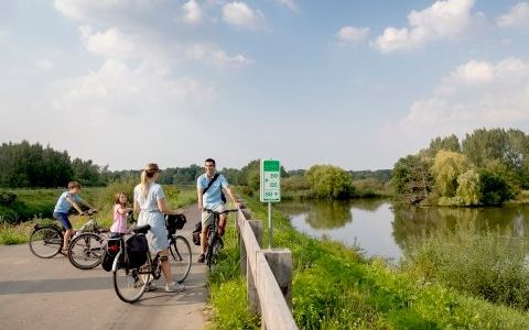 gezin op de fiets aan het water naast een knooppuntbord