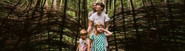 Een gezin met twee jonge kinderen gaat een wilgenhut in het Trollenbos van De Schorre in Boom binnen. Het wilgenriet is niet aansluitend, waardoor er licht binnenkomt, voornamelijk langs de bovenkant. De vrouw kijkt naar de dakconstructie boven haar dat licht doorlaat. Ze moedigt de kinderen met een klein duwtje in de rug aan om verder te wandelen, terwijl haar man achter haar volgt. De kinderen kijken vol bewondering rondom zich.